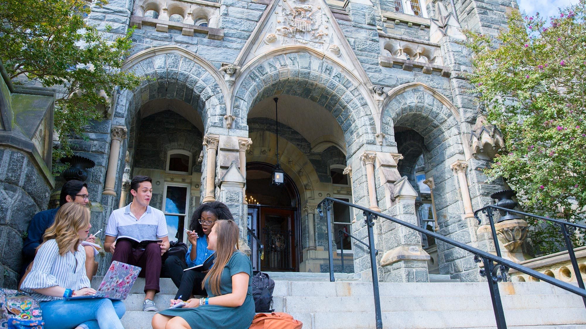 Students sit on the steps of Healy Hall.