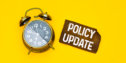 clock on yellow background with sign that says policy update