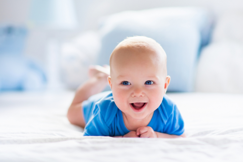 baby laying on tummy with head lifted to smile at the camera