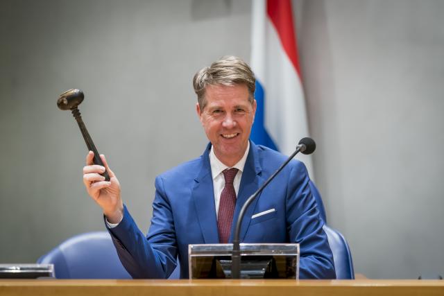 Chairman Martin Bosma is seated at the President's seat in front of the Dutch flag. In his right hand he is holding the chairman's hammer.