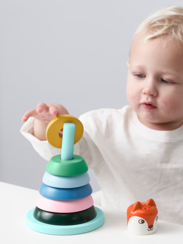 A child playing with multicolor UPPSTÅ stacking rings toy.