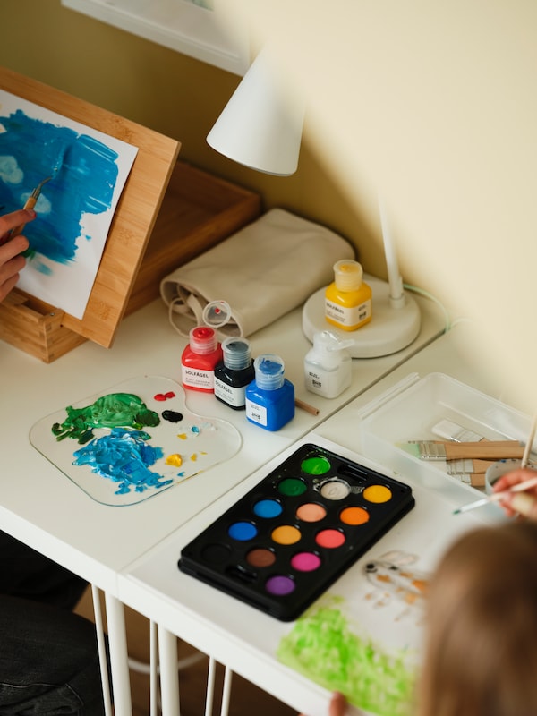 Kids art supplies sitting on a table, paint palette and artwork