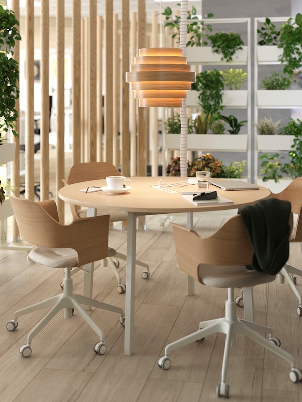 A meeting area with wooden floors, a MITTZON conference table and potted plants placed on a frame with castors.