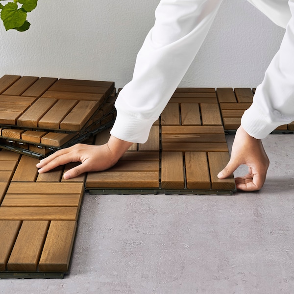 A woman clicking together brown RUNNEN deck tiles.