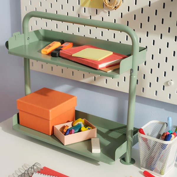 A green desk organizer with post-its and accessories on it.