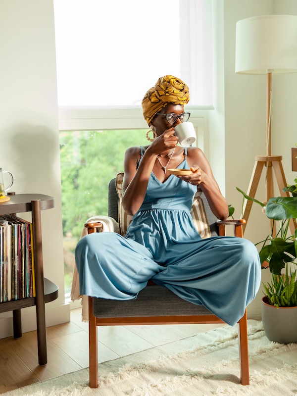 A relaxed woman sits in an armchair, sipping tea from an IKEA 365+ mug.