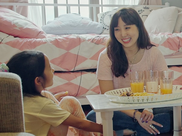 A mother and child enjoy a snack together, sitting at a low table on the bedroom floor.