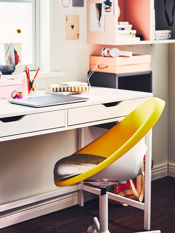 A workstation with a youthful vibe with pink accents and an ELDBERGET/MALSKÄR swivel chair in yellow and white.