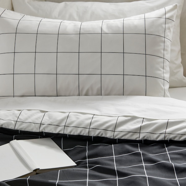 Black and white striped bed textiles made on a bed with a notebook sits on top of the comforter.