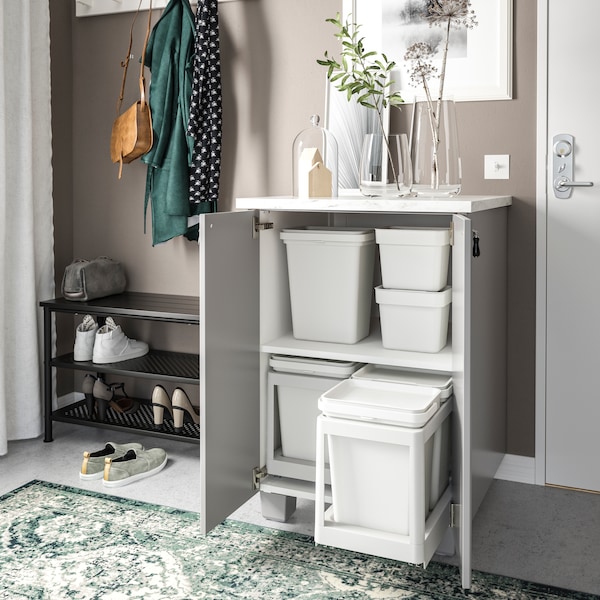 A cabinet with a pull-out trash bin and more bin organizers inside of it.