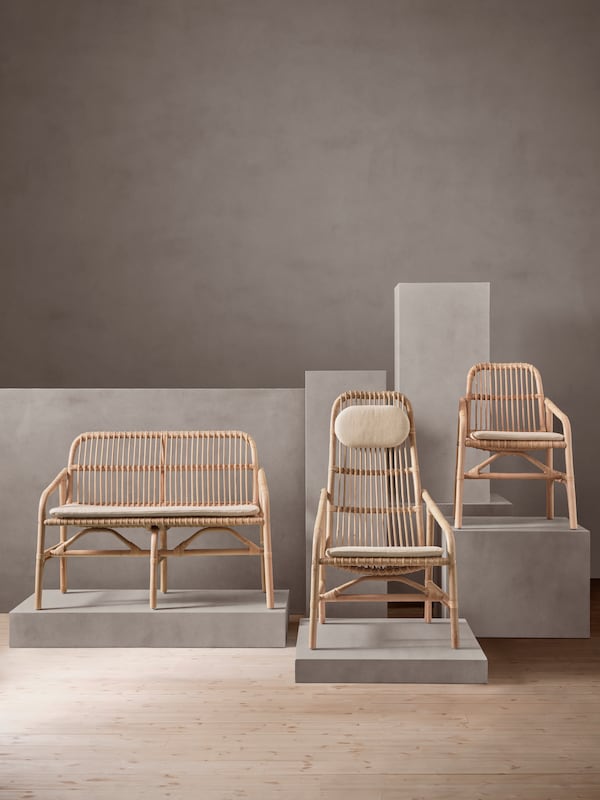 A SALNÖ bench, armchair with cushion and chair with armrests sit on light green and pink pedestals in a darker green room.