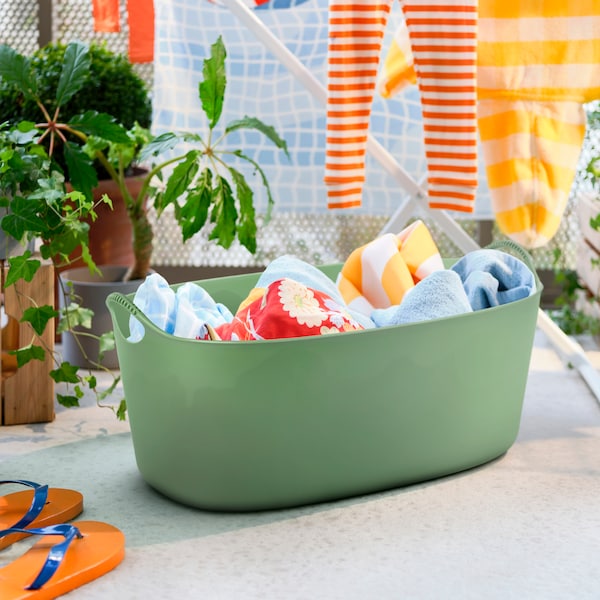 A green laundry basket filled with clothes.