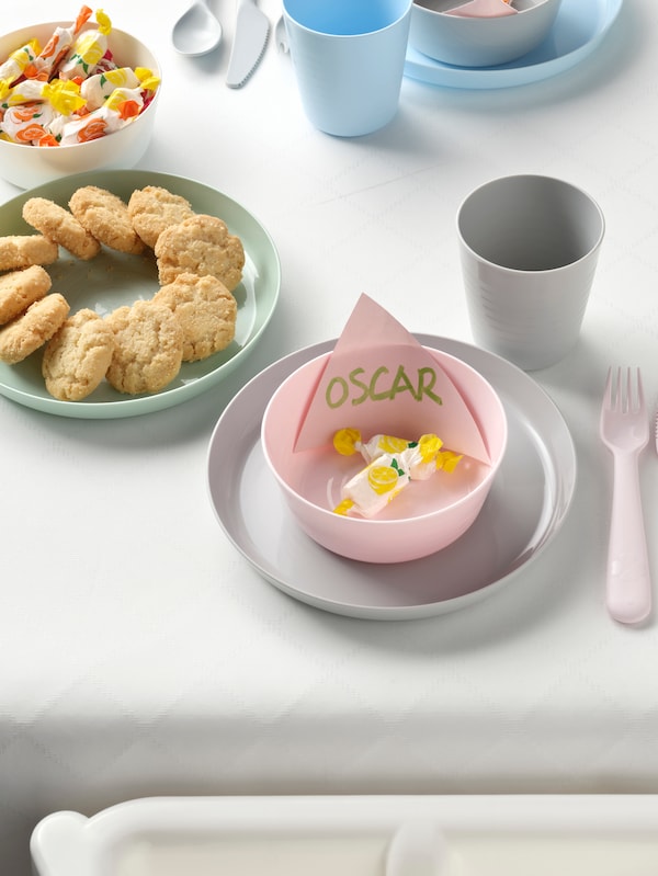 Kids plates and bowls sitting on a table with cookies on the plate and candy filling the bowls