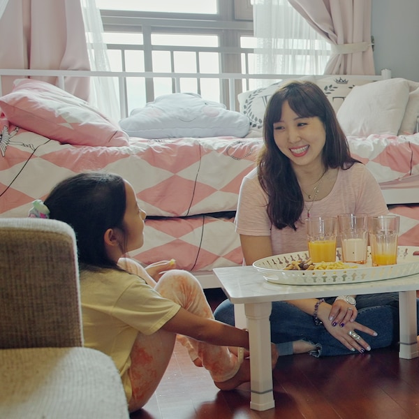 A mother and child enjoy a snack together, sitting at a low table on the bedroom floor.