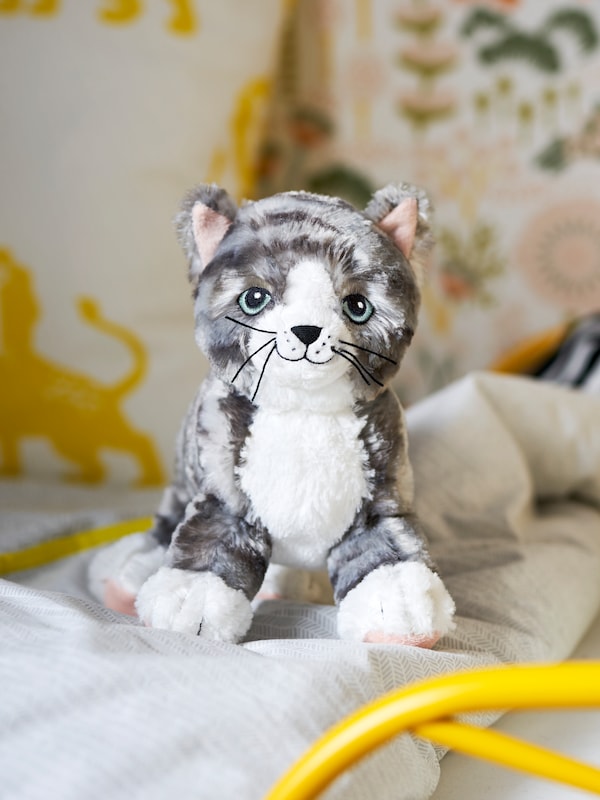 A cat soft toy placed on top of a bed