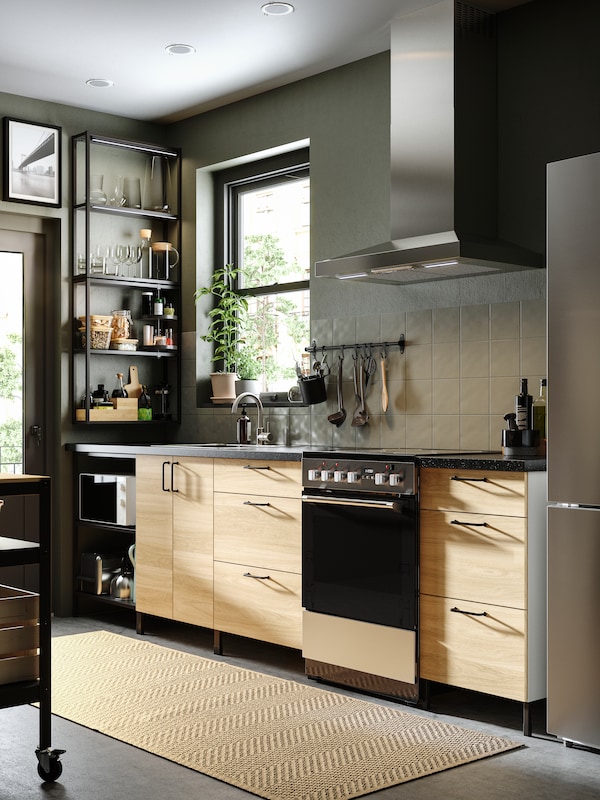 A modern kitchen with gray walls and floors, an ENHET kitchen in anthracite and fronts in oak effect and black wall shelves.