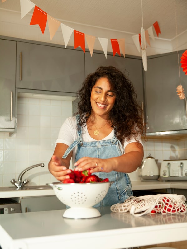 A woman rinses strawberries in a GEMAK colander.