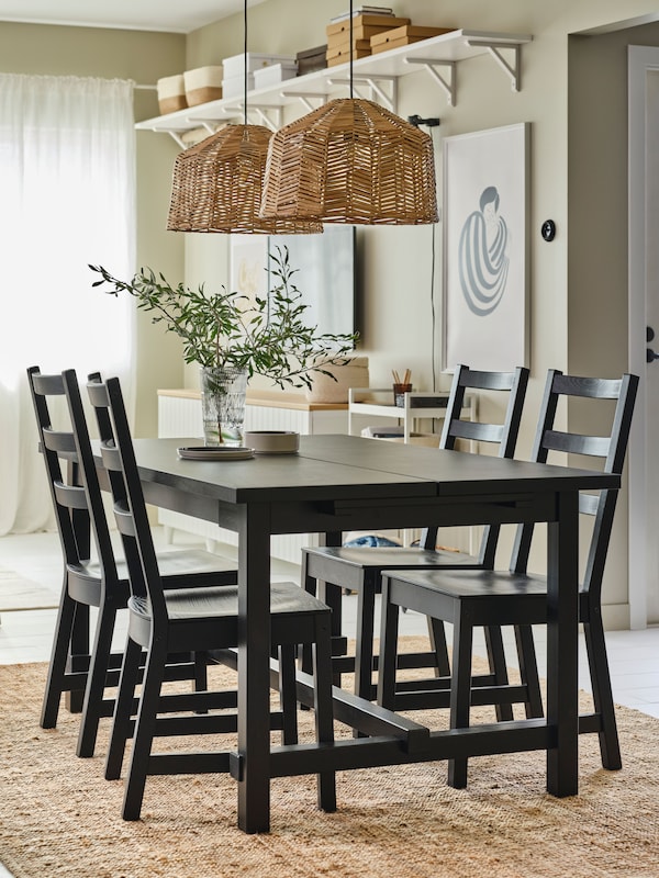 In a traditional dining room is a spacious NORDVIKEN wood dining table in black with four chairs. Two pendant lamps.