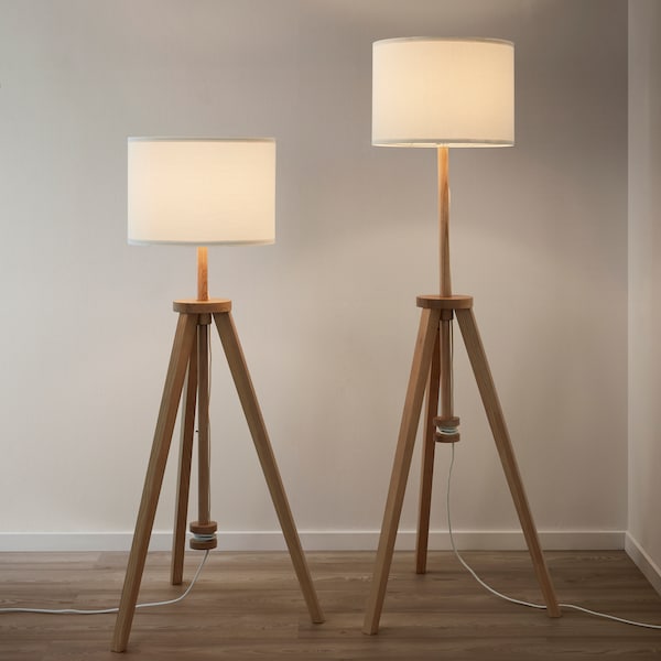 Two lamps with white shades side by side and one is adjusted to a higher height than the other.