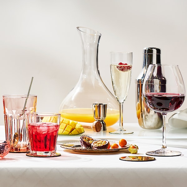 A wine glass, a champagne glass, two drinking glasses and a clear glass carafe, on a table with a white tablecloth.