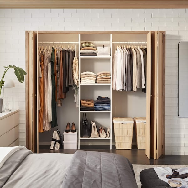 An organized closet with clothes folded and hanging in it.