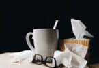 white ceramic mug on white table beside black eyeglasses