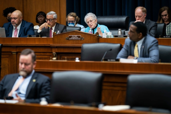 Virginia Foxx, in a bright teal blazer, sits behind a dais.