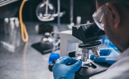 Photo of man looking at slides under a microscope