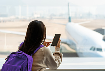 person sitting at the airport looking at their mobile phone