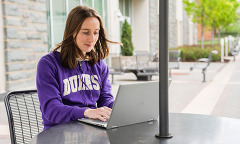 Student studying outdoors on a laptop at a table