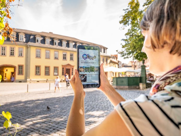 Frau mit Tablet auf dem die App Weimar+ geöffnet ist