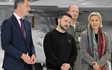 Le Premier ministre belge Alexander De Croo (à gauche), le président ukrainien Volodymyr Zelensky (au centre) et la ministre belge de la Défense Ludivine Dedonder (à droite) écoutent pilotes, instructeurs et techniciens belges de F-16  à l'aéroport militaire de Melsbroek. AFP/Belga/ERIC LALMAND.