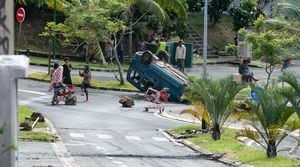 Des habitants se rassemblent autour d'une voiture retrounée dans le quartier de Moto Pool à Nouméa, en Nouvelle-Calédonie le 16 mai 2024 