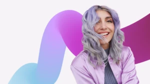 Portrait of a woman smiling with hair in her face in front of a decorative background.