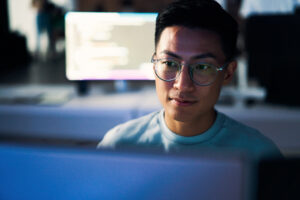 Computer coding, programming and asian man in cybersecurity, software development and html script. Night person from china with information technology career, database code and monitor network safety