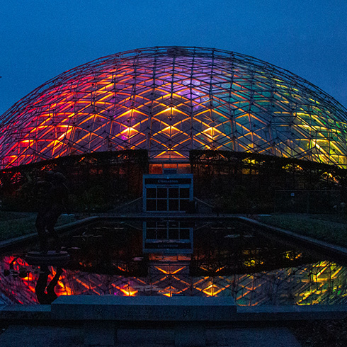 Climatron conservatory dome glowing with multiple colors at twilight