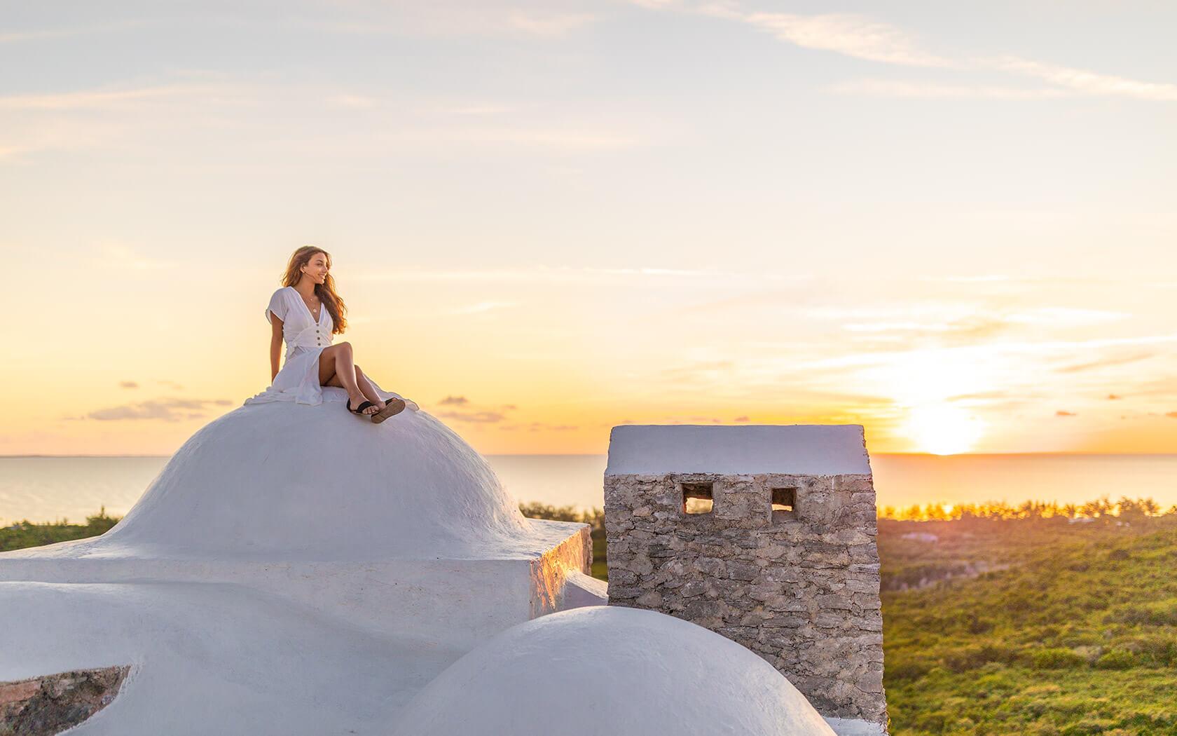 woman sitting on a roof watching the sunset