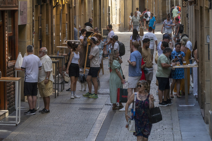 Una calle de la Parte Vieja de Donostia, repleta de mesas altas y taburetes de bares y restaurantes.