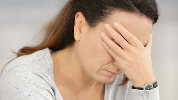 Eine Frau beugt den Kopf nach vorne und fasst sich an die Stirn. © COLOURBOX Foto: Phovoir