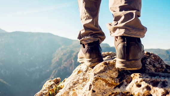 Die Füße eines Wanders mit Wanderschuhen, auf einem Felsen stehend © picture alliance / Shotshop | Addictive Stock 