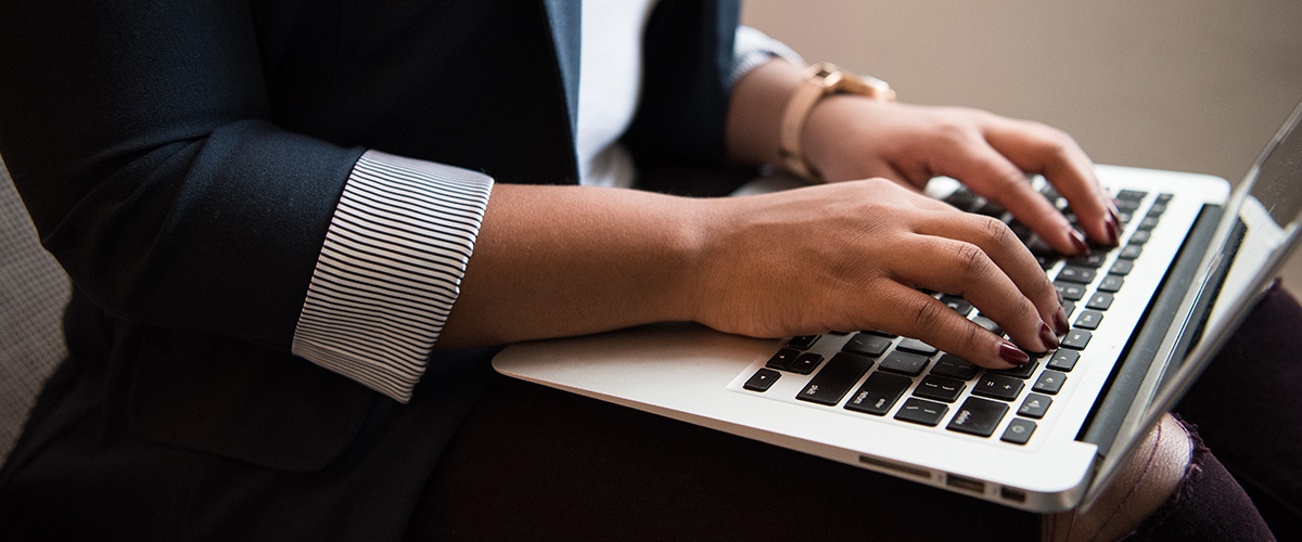 Close up photograph of a person typing on their laptop