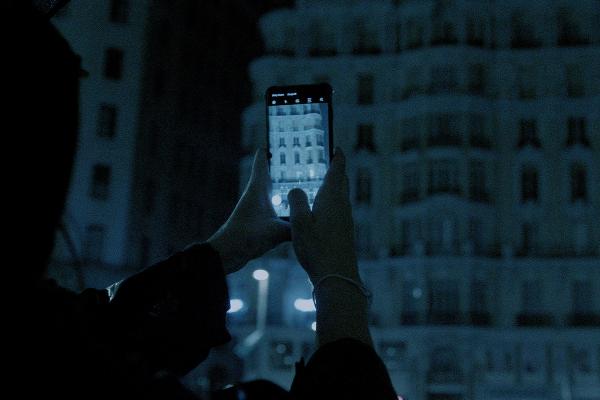 Person taking a photo on their phone in at nighttime outside in the dark