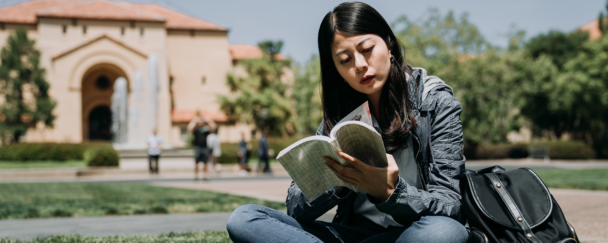 a college student reading a book on campus