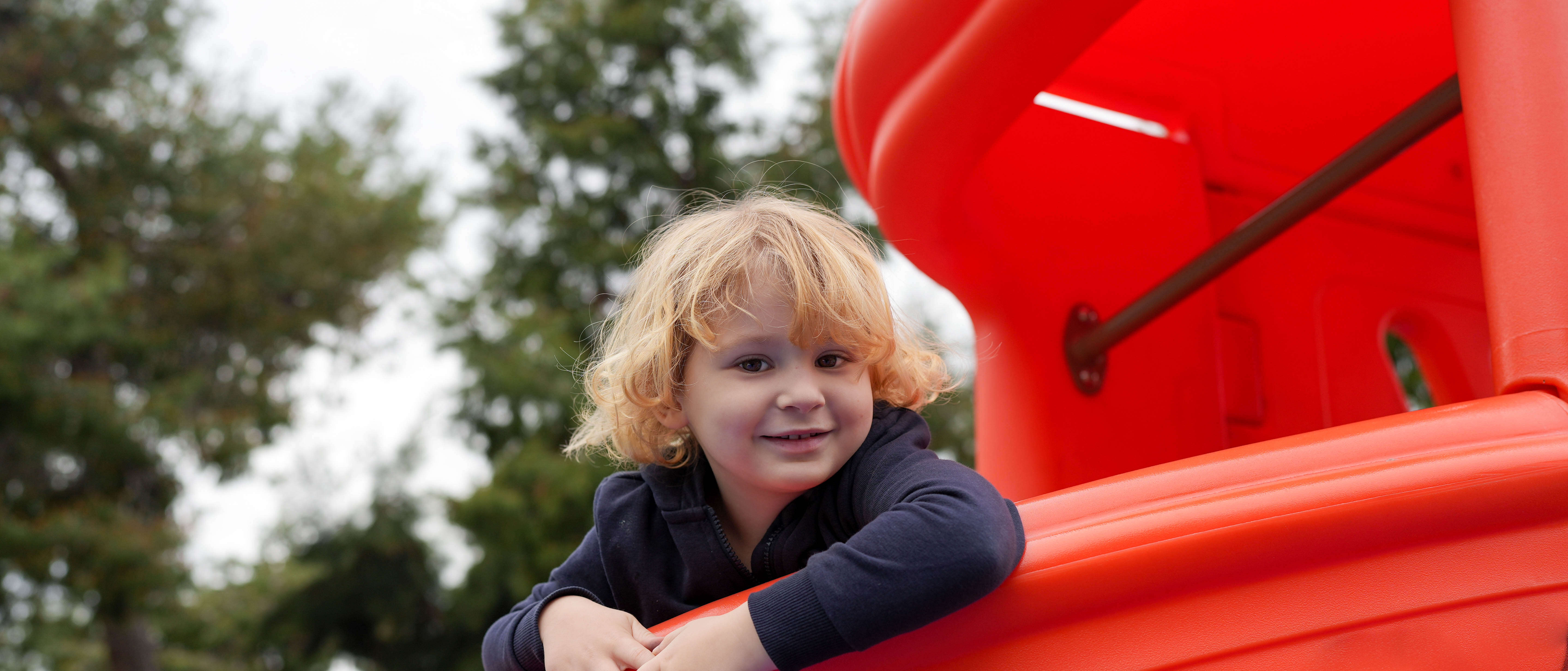 A child smiles while playing at a playground.