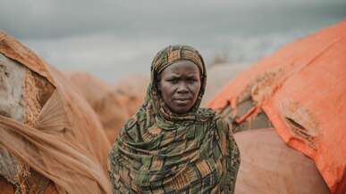 A woman poses solemnly for a photo outside of a makeshift shelter in Somalia.