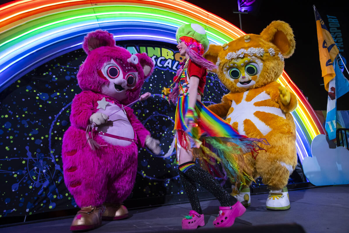 A festival attendee dances with costumed entertainers during the second night of the Electric D ...