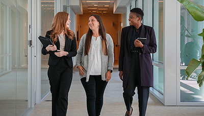 Group of business professionals walking down a hallway talking.