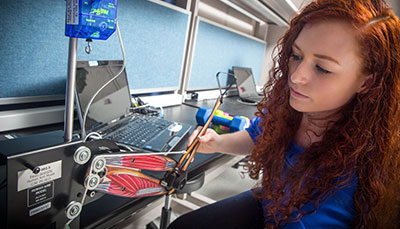 A student in a lab working with an artificial arm model.