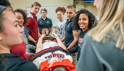 A group of students examining a mannequin and discussing with each other.