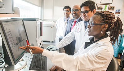 Students and professor looking at computer.